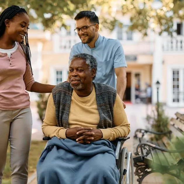 Two adult children with their father in a wheelchair
