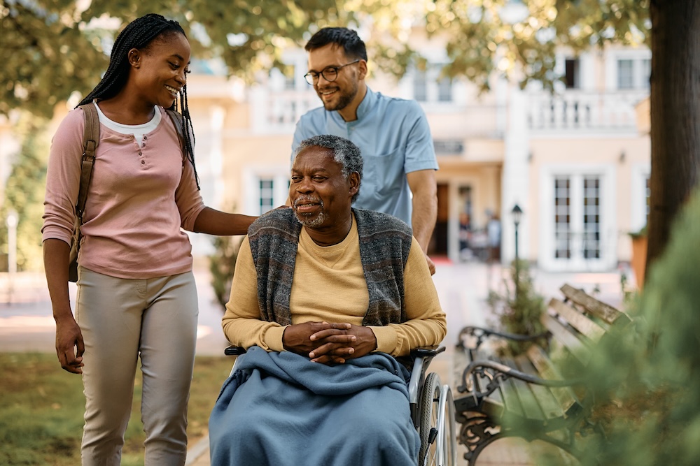Two adult children with their father in a wheelchair